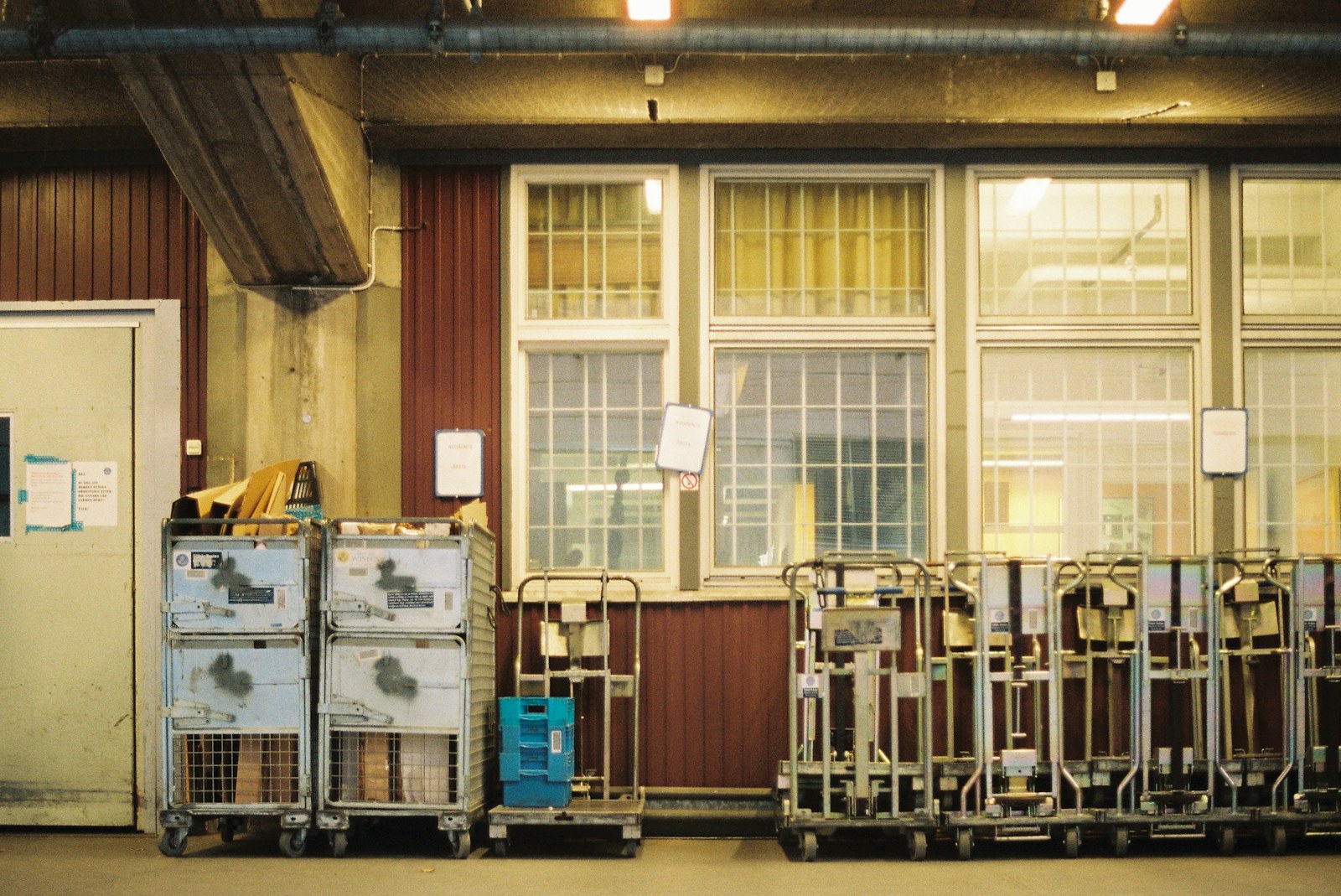 An industrial interior with equipment carts and overhead pipework.